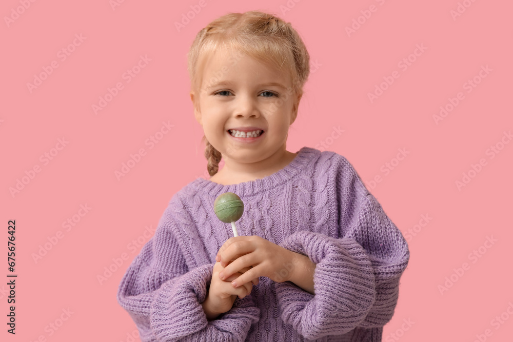 Cute little girl with sweet lollipop on pink background