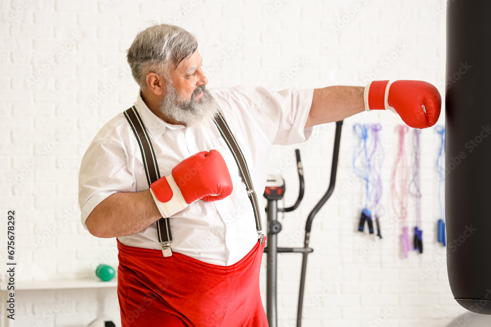 Sporty Santa Claus with boxing gloves training in gym