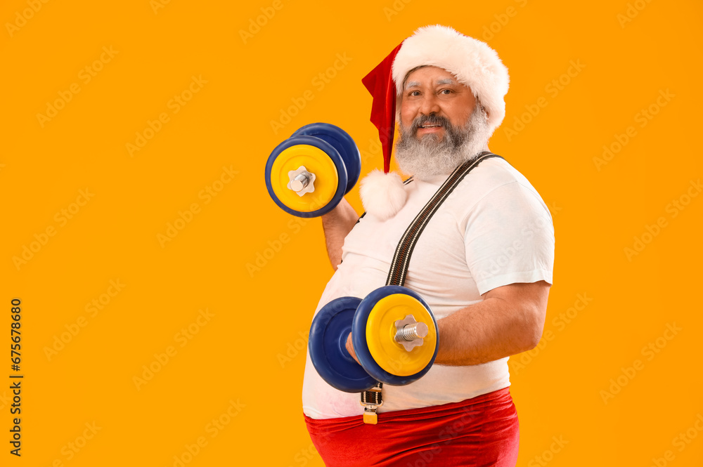 Sporty Santa Claus with dumbbells on yellow background