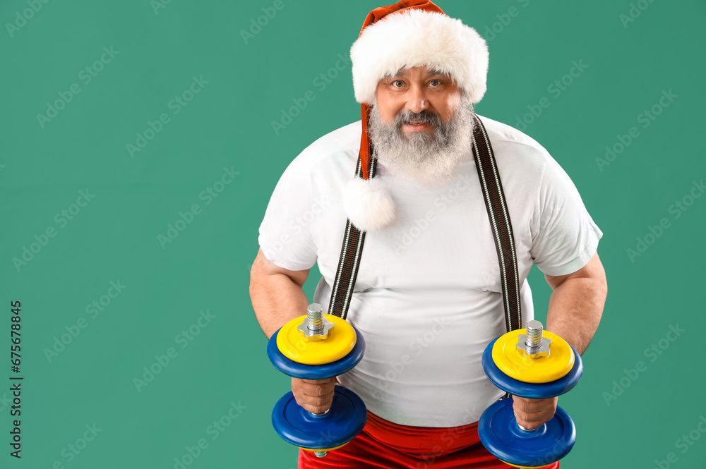 Sporty Santa Claus with dumbbells on green background