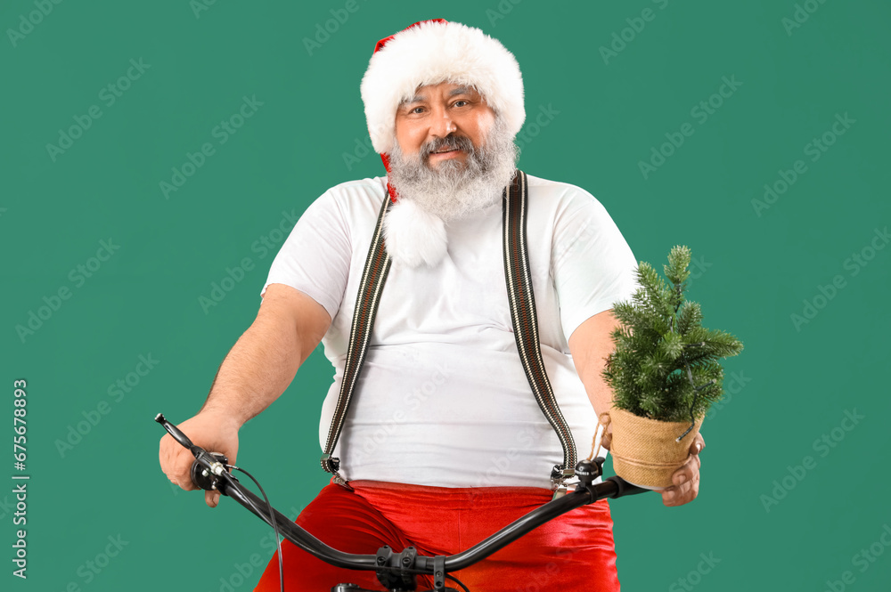 Sporty Santa Claus with Christmas tree riding bicycle on green background