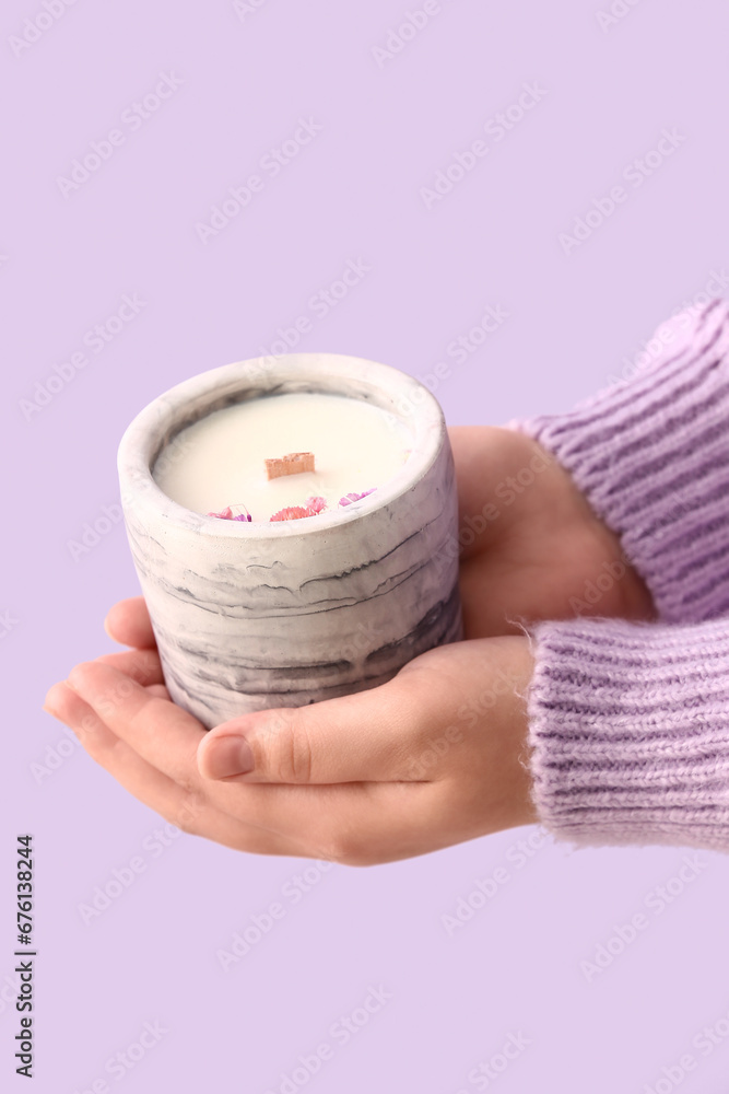 Woman holding candle on purple background, closeup