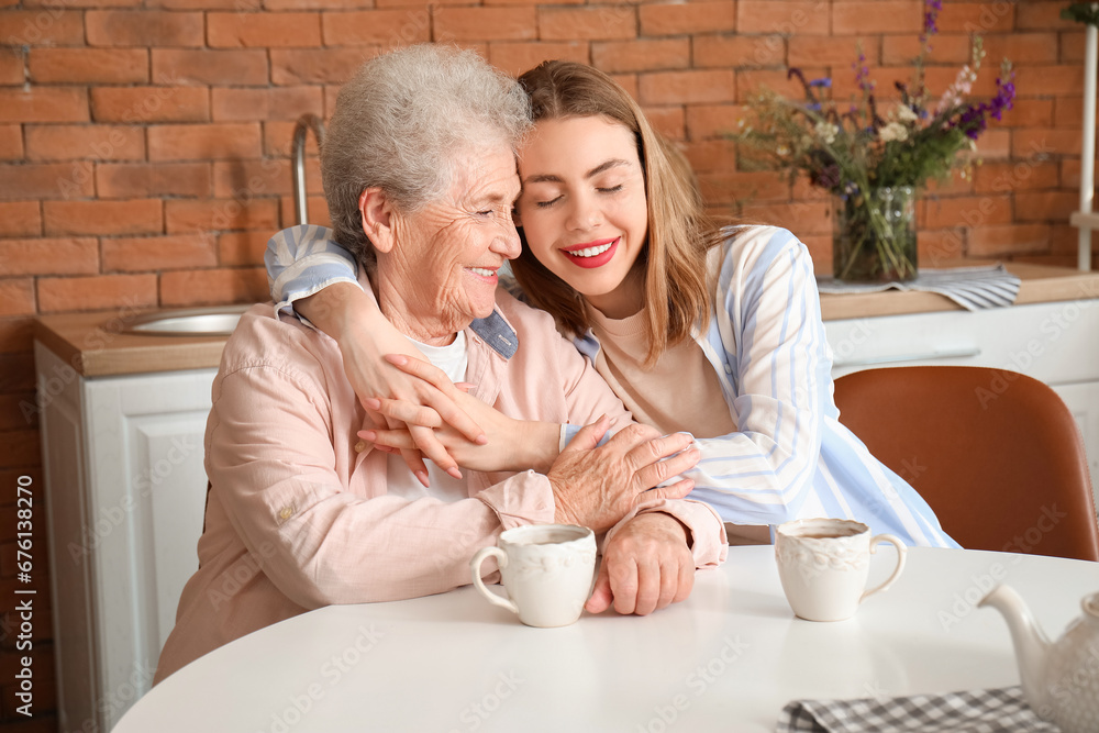 Young woman with her grandmother hugging in kitchen