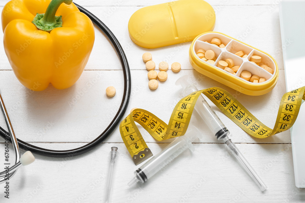 Composition with pills, syringes, and measuring tape on white wooden background