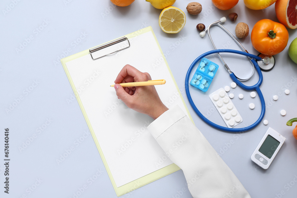 Female doctors hand with clipboard, pills and healthy products on grey background