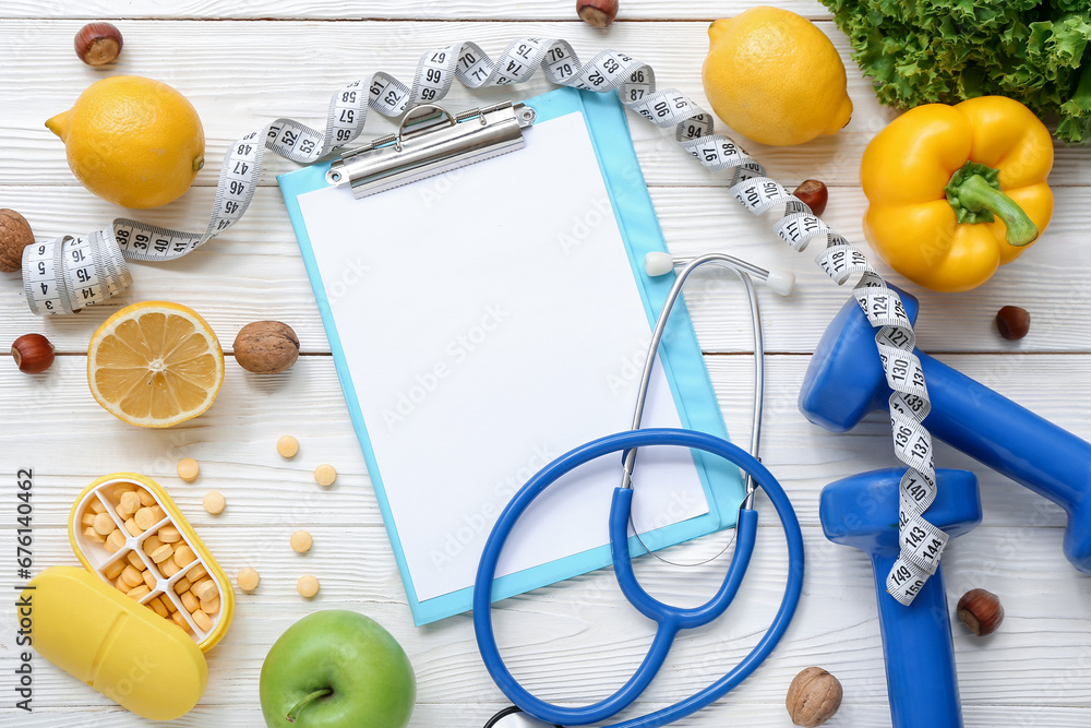 Composition with blank clipboard, measuring tape, pills and healthy products on white wooden background