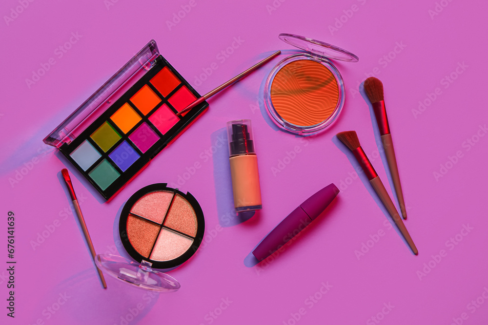 Beautiful palettes of eyeshadows and different decorative cosmetics on purple background