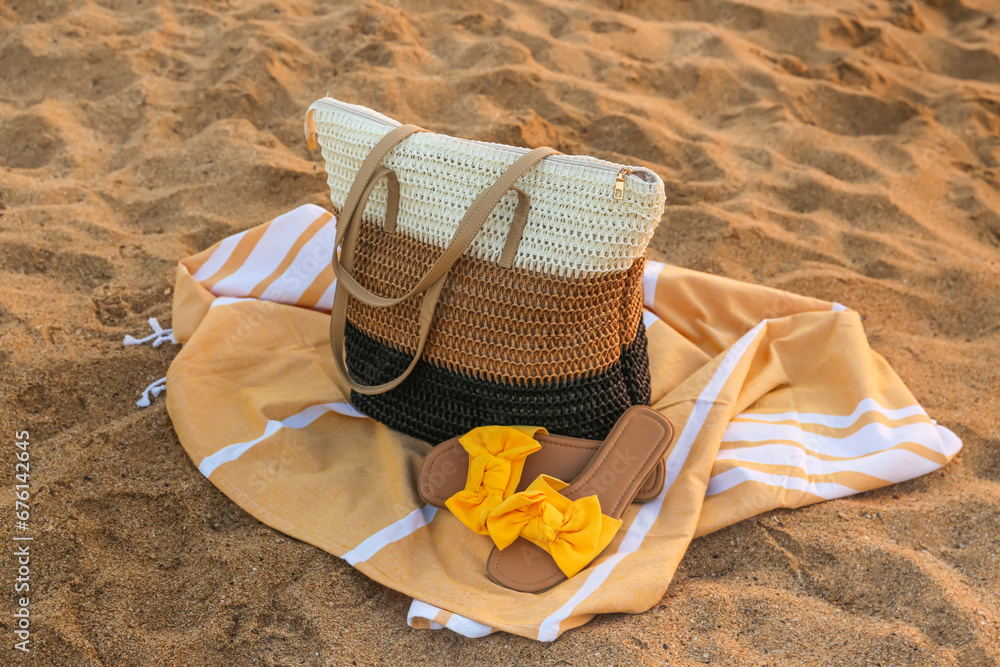 Stylish beach bag, towel and female shoes on sand