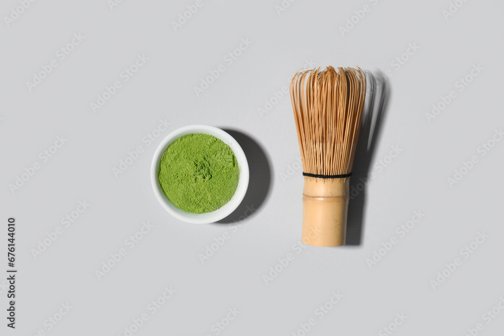 Bowl of powdered matcha tea and chasen on grey background