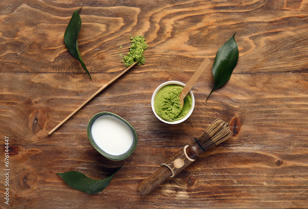 Composition with powdered matcha tea, milk and accessories on wooden background