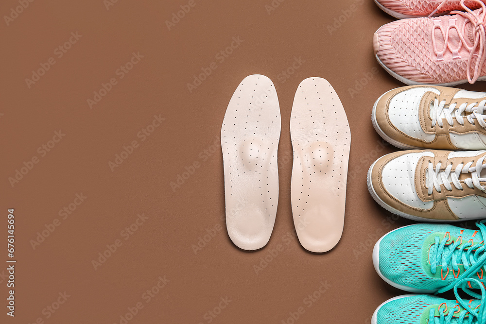 Set of different sneakers and orthopedic insoles on color background