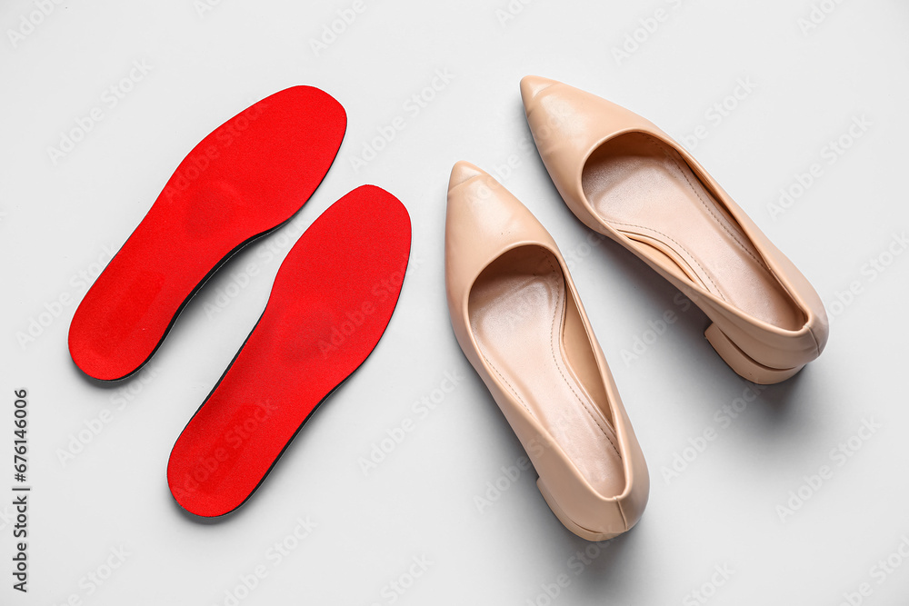 Pair of stylish female shoes and orthopedic insoles on grey background