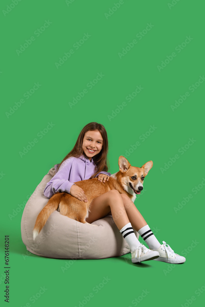 Little girl with cute Corgi dog sitting on green background