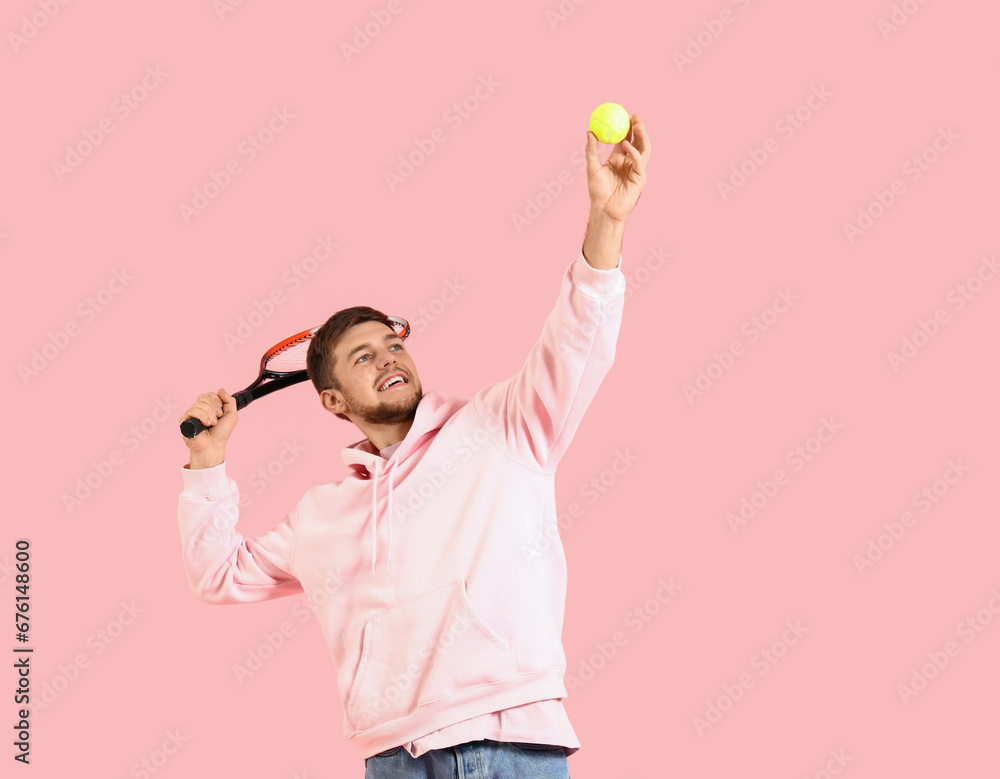 Young bearded man playing tennis on pink background