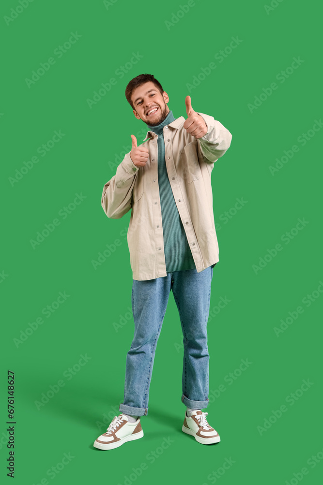 Young bearded man showing thumbs-up on green background