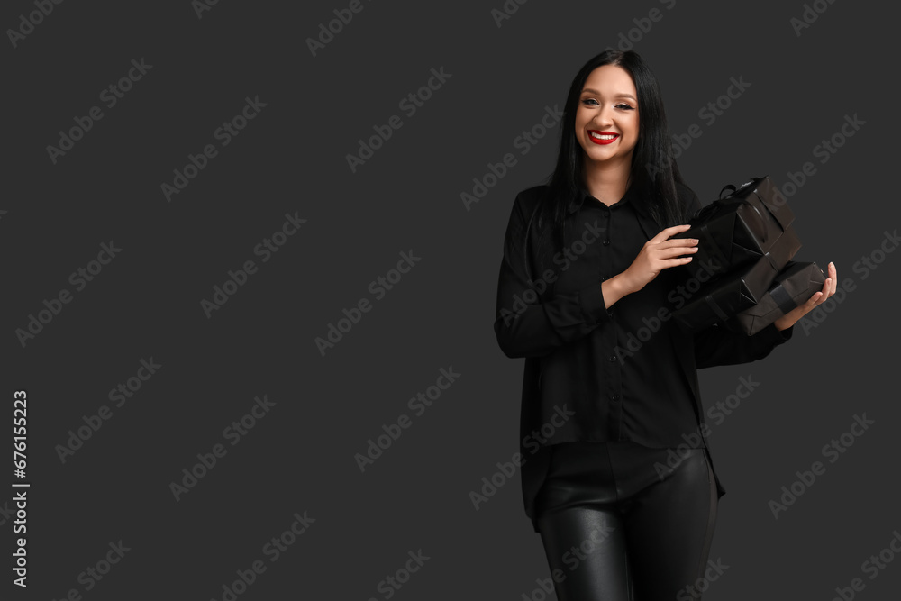 Beautiful stylish woman with gift boxes on dark background. Black Friday Sale