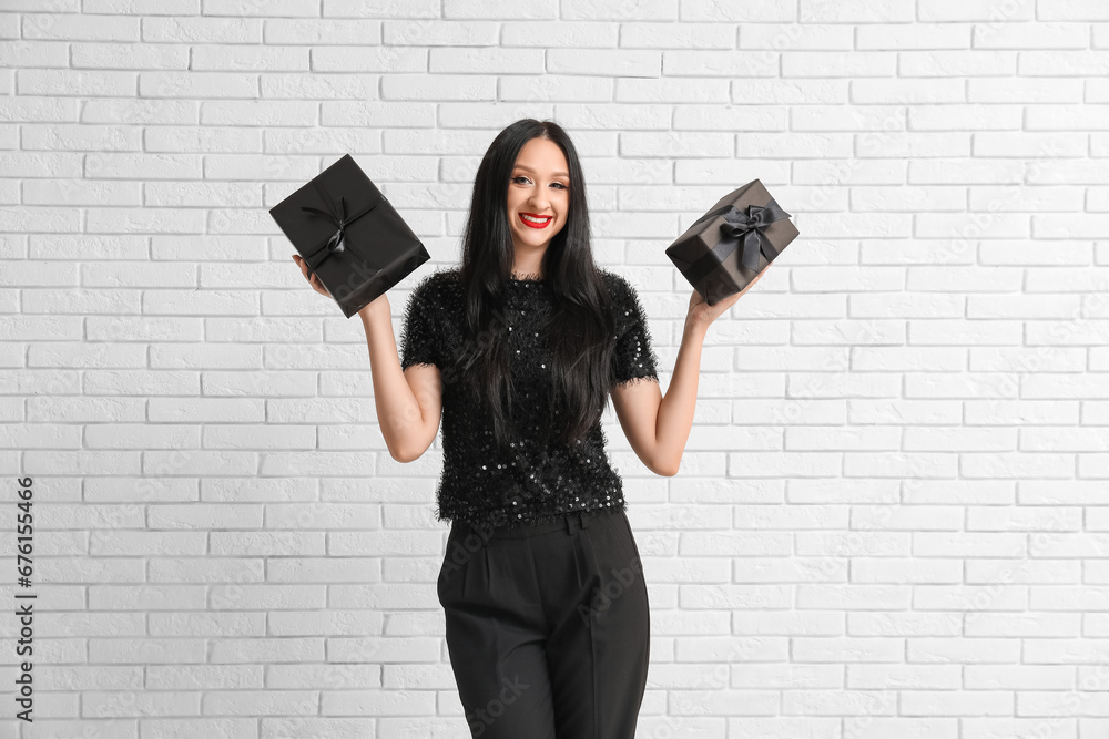 Beautiful stylish woman with gift boxes on white brick background. Black Friday Sale