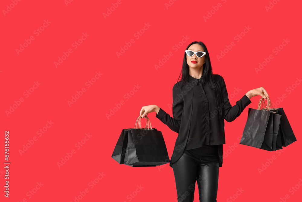 Beautiful stylish woman with shopping bags on red background. Black Friday Sale