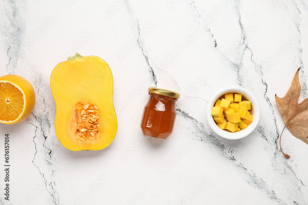 Jar of sweet pumpkin jam with orange and autumn leaf on white background