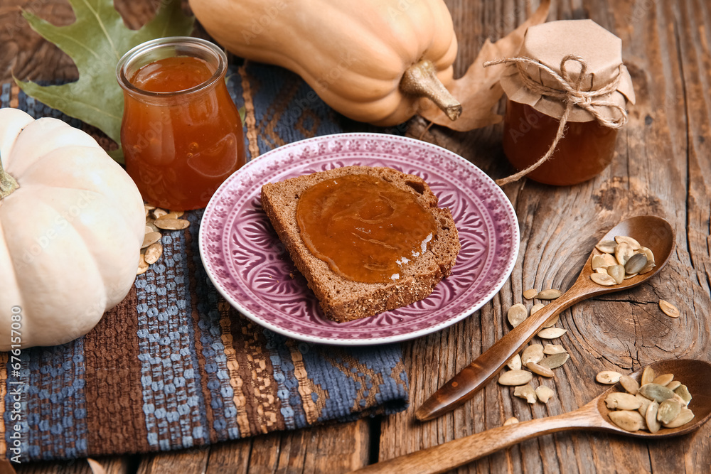 Plate of toast with sweet pumpkin jam and seeds on wooden background