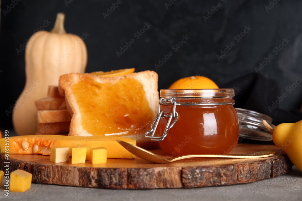 Jar and toast with sweet pumpkin jam on grey table