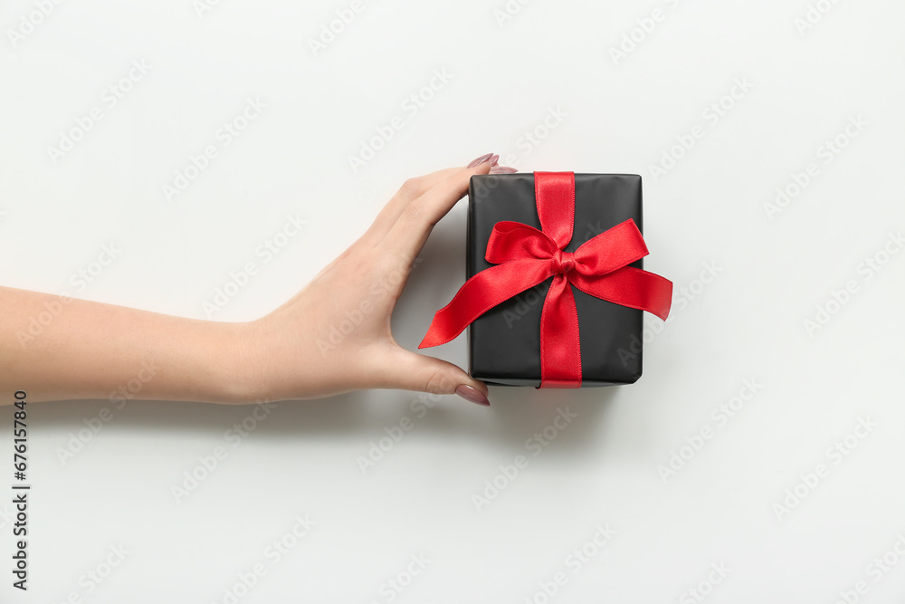 Female hand with gift box on white background. Black Friday