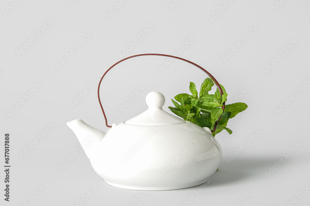 Teapot of fresh mint tea on grey background