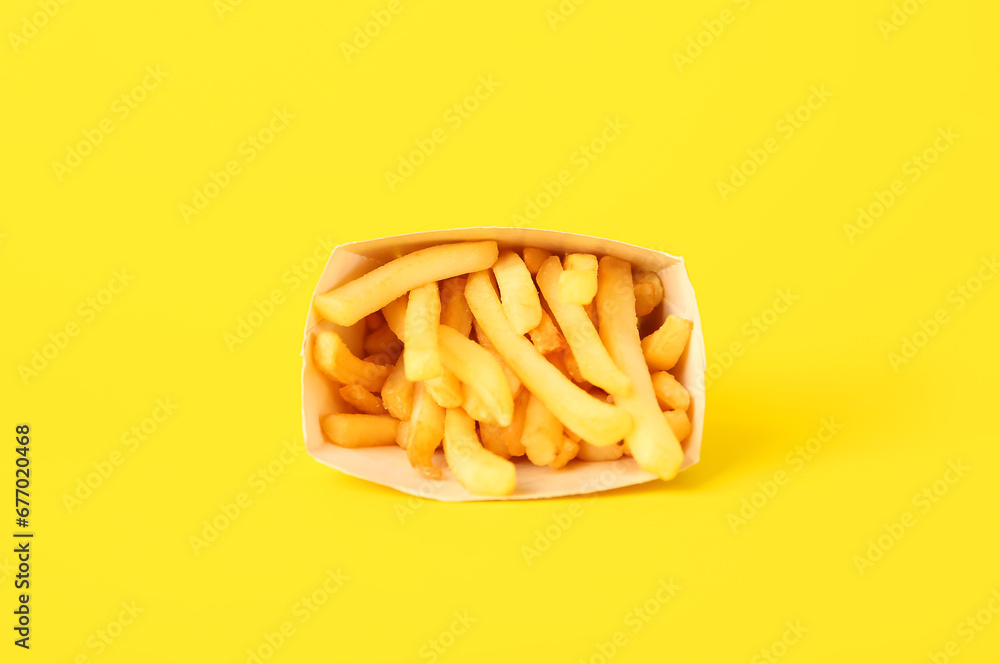 Paper box with delicious french fries on yellow background