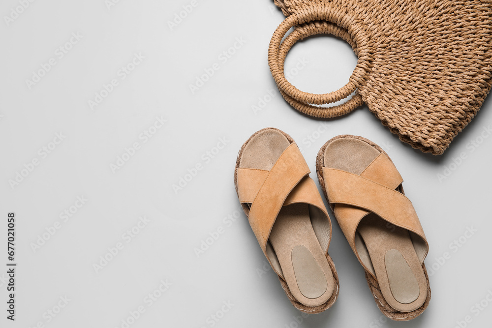 Stylish beige sandals and wicker bag on grey background