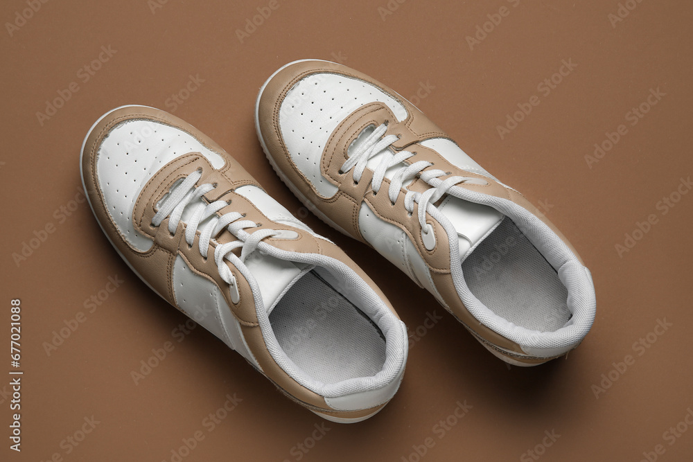 Stylish sneakers on brown background