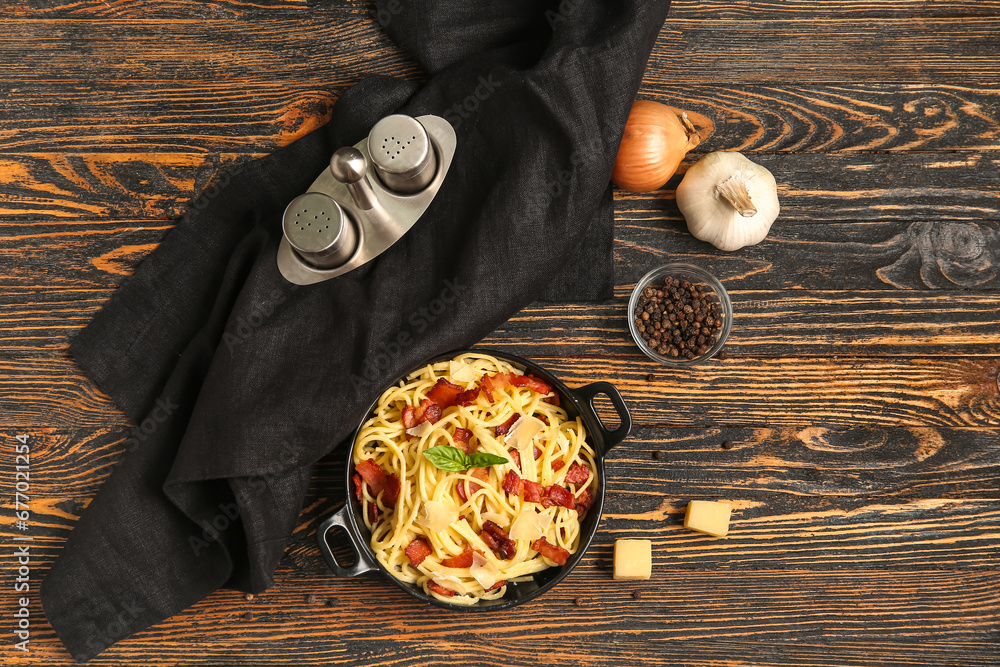 Frying pan with tasty pasta carbonara on wooden background