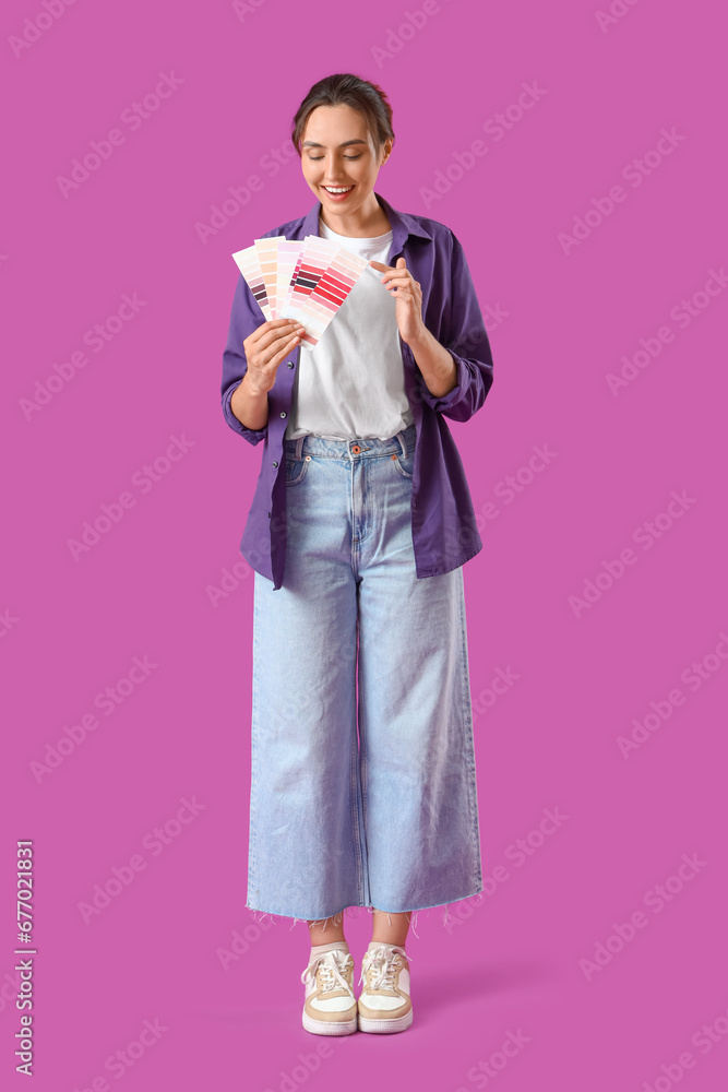 Young woman with paint color palettes on purple background