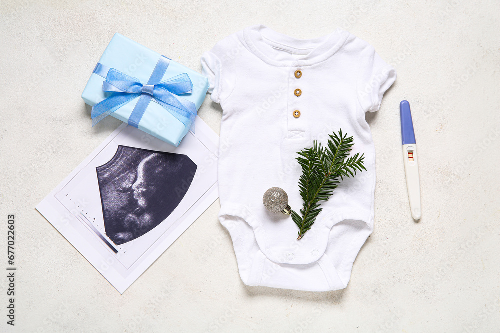 Composition with baby clothes, sonogram image and Christmas gift on light background