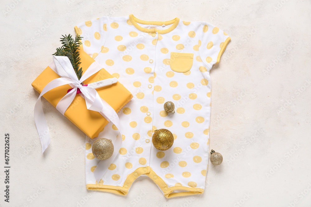 Composition with stylish baby clothes, Christmas gift and balls on light background