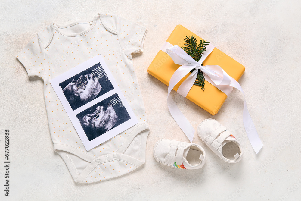 Composition with stylish baby clothes, sonogram image and Christmas gift on light background