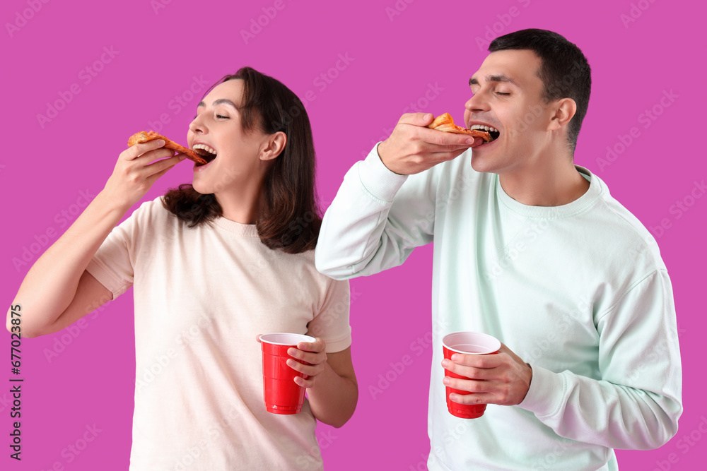 Young couple eating tasty pepperoni pizza on purple background