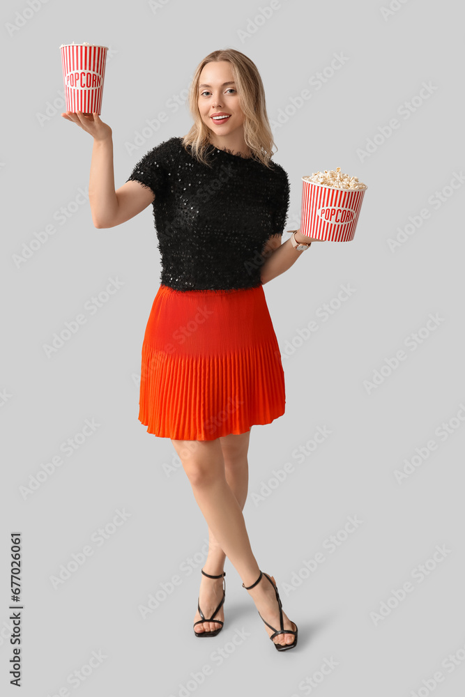 Young woman with buckets of popcorn on white background