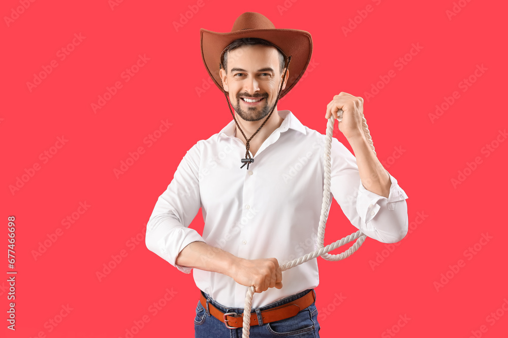 Handsome cowboy with lasso on red background