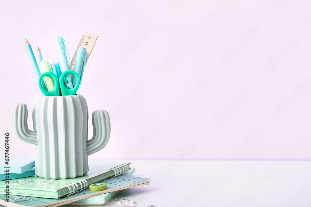 Holder with different stationery on light desk, closeup