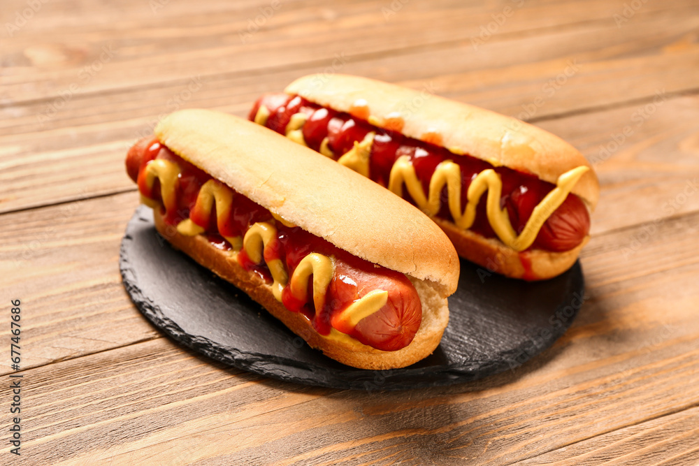 Board with tasty hot dogs on wooden background