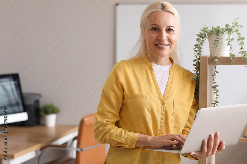 Mature female programmer working with laptop in office