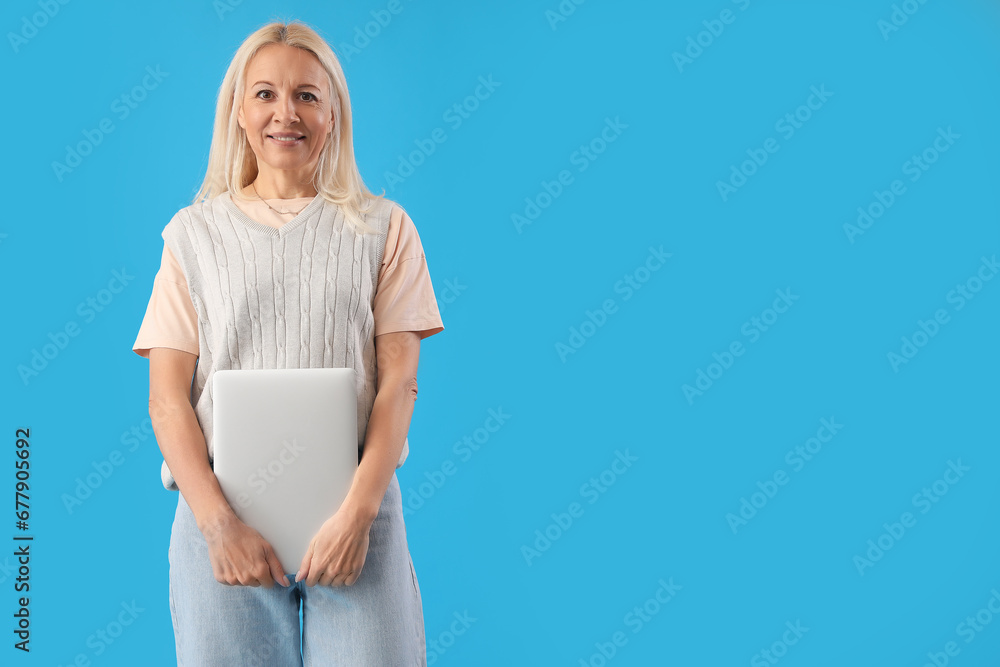 Mature female programmer with laptop on blue background