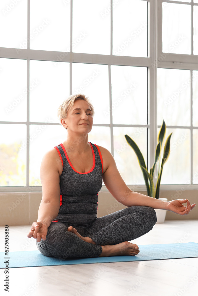 Sporty mature woman practicing yoga at  home