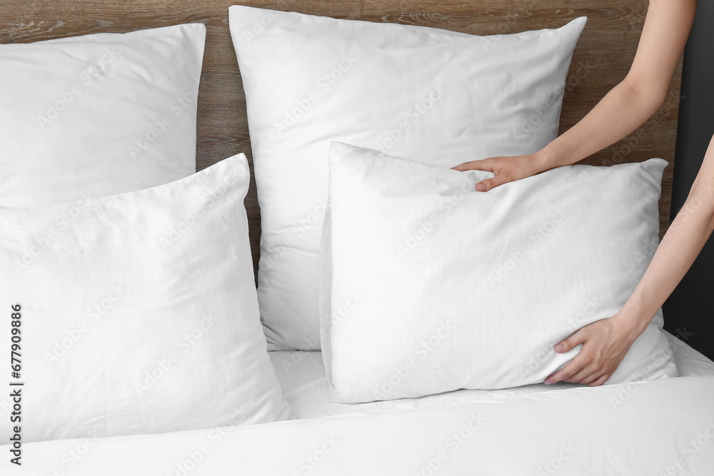 Chambermaid making bed in hotel room