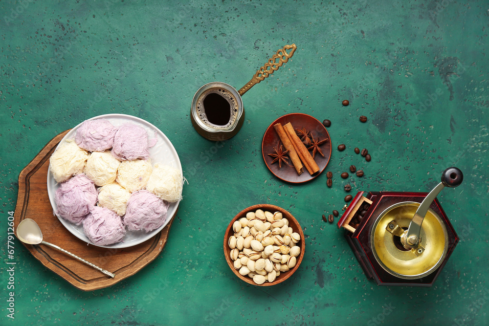 Plate of tasty Turkish Pismaniye, nuts, cezve with coffee and grinder on green background