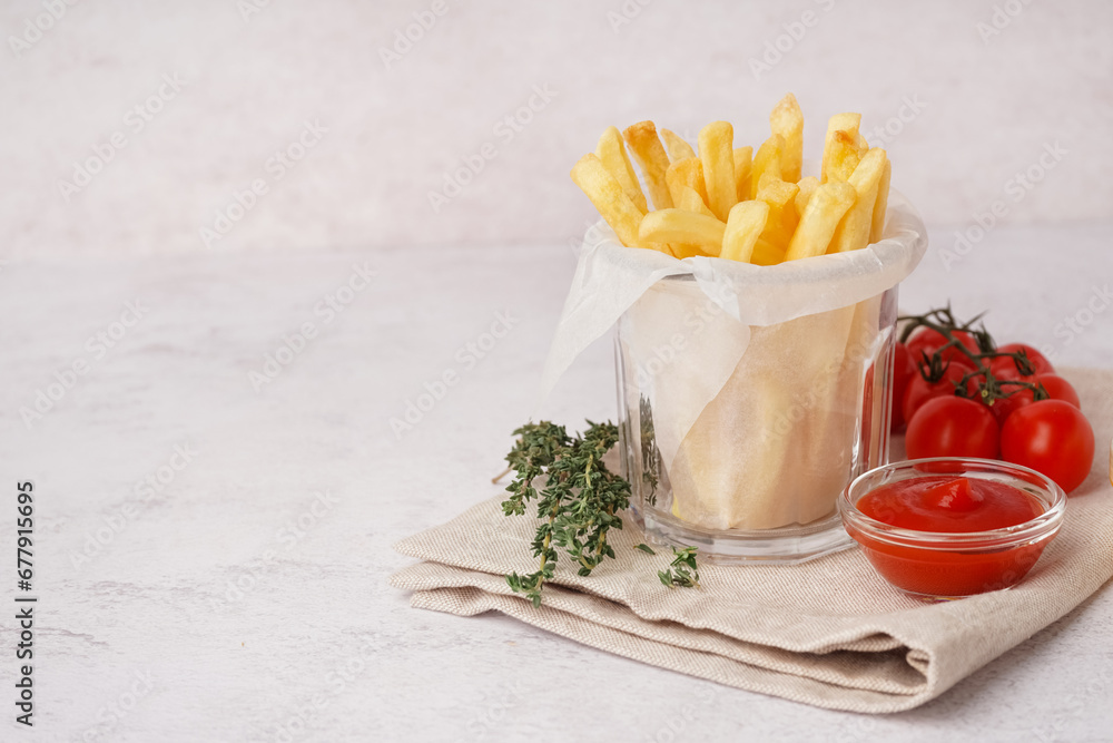 Glass with tasty french fries and ketchup on white background