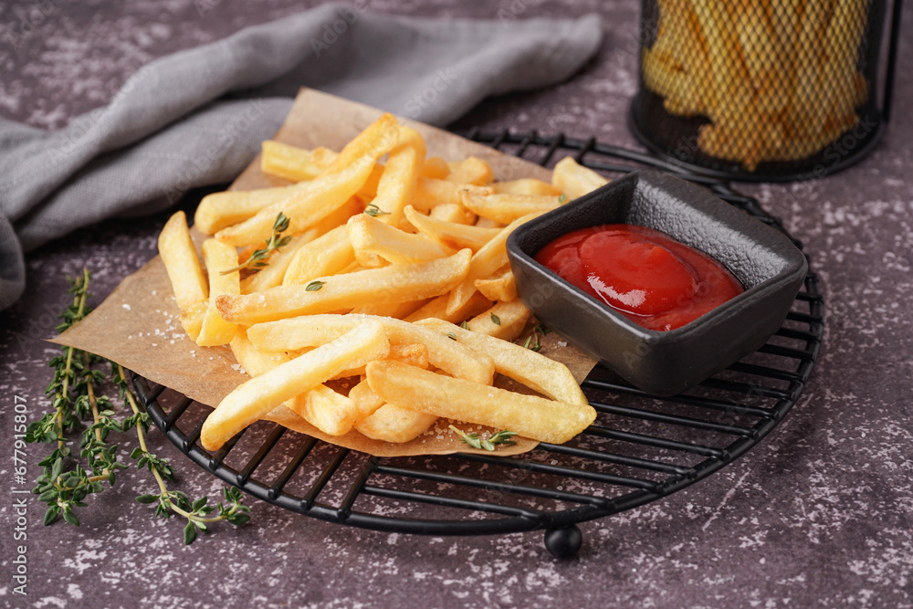 Grid with tasty french fries and ketchup on grey background