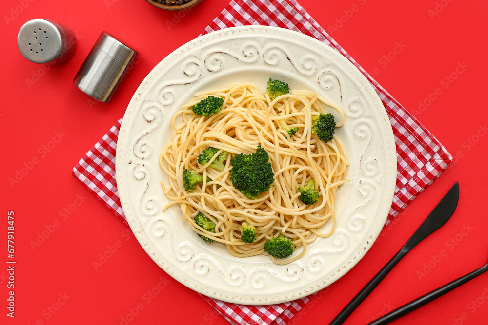 Plate of tasty pasta with broccoli on red background