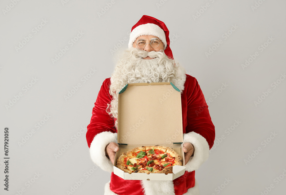 Santa Claus with box of tasty pizza on white background