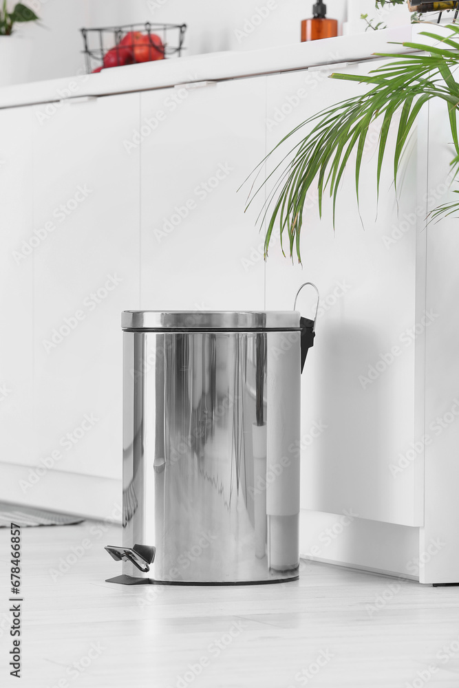 Metallic trash bin in interior of light kitchen